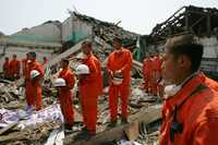 Policías, en labores de rescate, detienen los trabajos de búsqueda en un edificio derrumbado en la ciudad de Tashui para guardar tres minutos de silencio como señal de respeto por las víctimas del terremoto