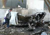 Un perito revisa los daños que ocasionó el avión de la Secretaría de Gobernación en un automóvil y un edificio sobre la calle de Ferrocarril de Cuernavaca, en las Lomas de Chapultepec