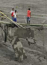 Habitantes de Laderas, Colombia, intentan cruzar por los restos de un puente destruido por la avalancha que generó la erupción del volcán Nevado de Huila